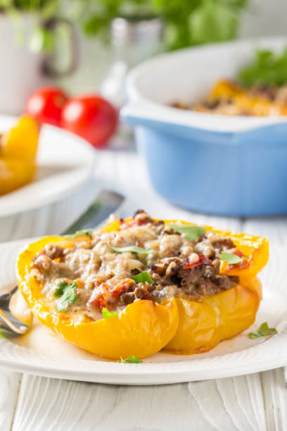 istock Stuffed yellow bell peppers, beef stew stuffing with vegetables and cheese. Light wooden background 1018735642