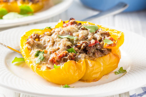 istock Stuffed yellow bell peppers, beef stew stuffing with vegetables and cheese. Light wooden background 1018735674
