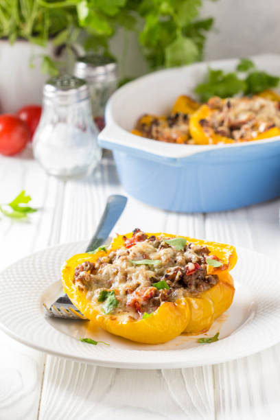 istock Stuffed yellow bell peppers, beef stew stuffing with vegetables and cheese. Light wooden background 1018735700