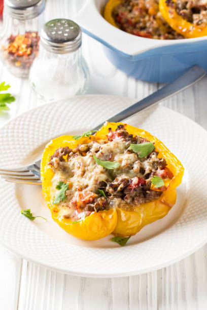 istock Stuffed yellow bell peppers, beef stew stuffing with vegetables and cheese. Light wooden background 1018735756
