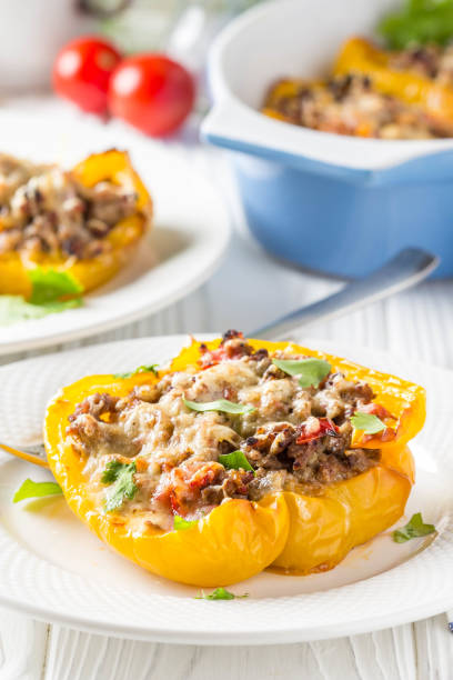 istock Stuffed yellow bell peppers, beef stew stuffing with vegetables and cheese. Light wooden background 1018735836