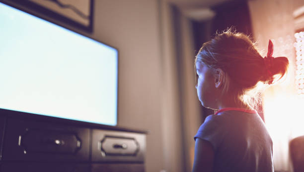 Little girl staring at TV Backview of blond girl watching TV at home one boy only stock pictures, royalty-free photos & images