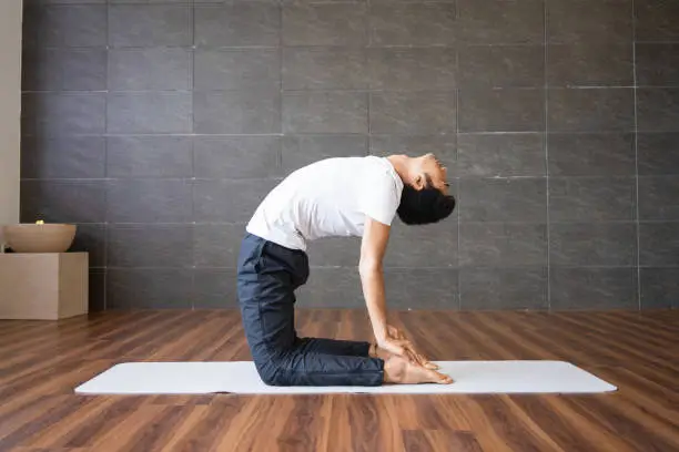 Photo of Yogi doing camel yoga pose in gym