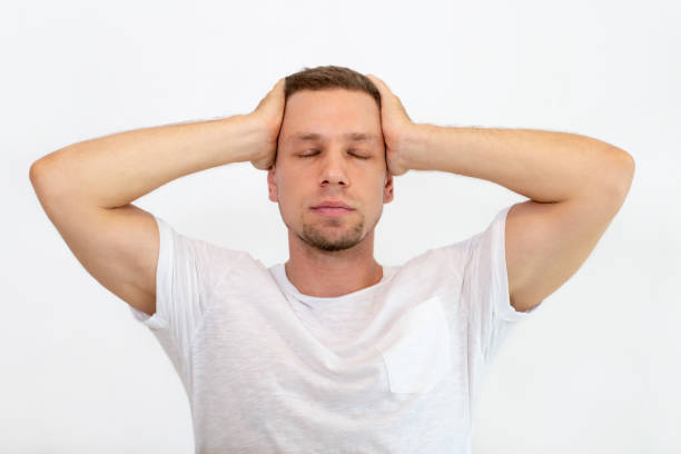 istock Exhausted young man holding head in hands while feeling pain 1018742894