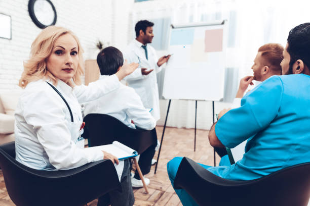 istock Female Doctor Points On Indian Colleague Lecture. 1018745852