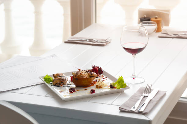 dinner or lunch with dish per one person. luxury white interior of restaurant. red wine and chicken at pear