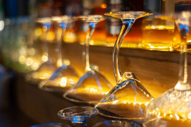 glass row bar counter . Many empty wineglasses. Yellow warm light