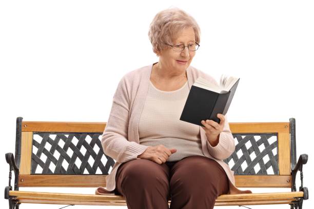 istock Elderly woman sitting on a bench and reading a book 1018758138