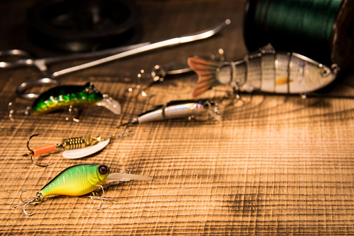 Fishing gear, artificial bait on a predator on a wooden background, top view wobblers and various bait cords and tongs with copyspace on a wooden background with .