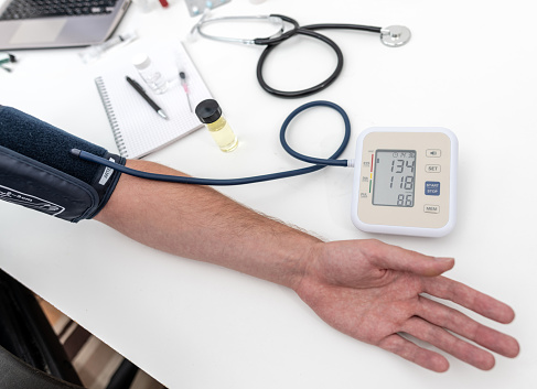 Using a digital blood pressure monitor on a male arm, with pulse rate on screen also