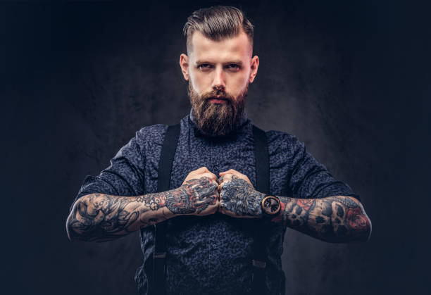 istock Severe old-fashioned hipster guy in a blue shirt and suspenders, posing in a studio. 1018768182