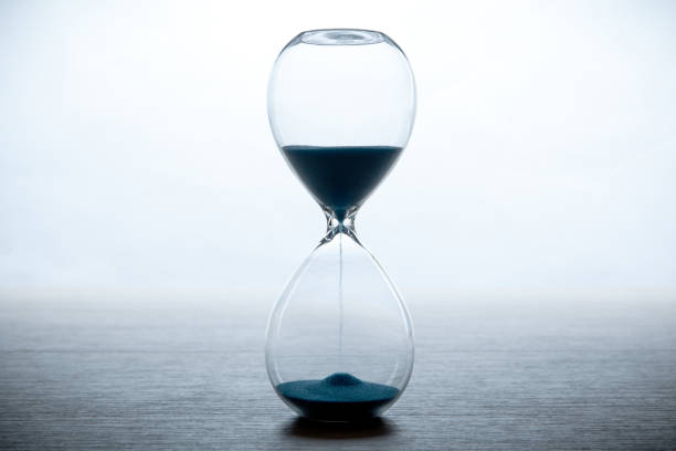 istock hourglass with blue sand on a white background and a gray table close up 1018787800