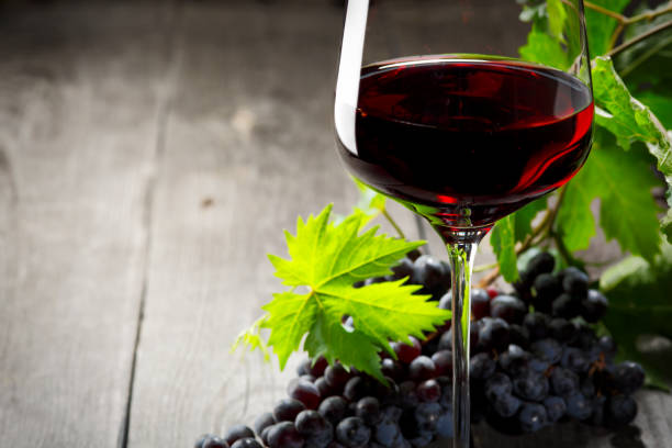 istock Red wine and grapes. Wine and grapes in vintage setting with corks on wooden table 1018792064