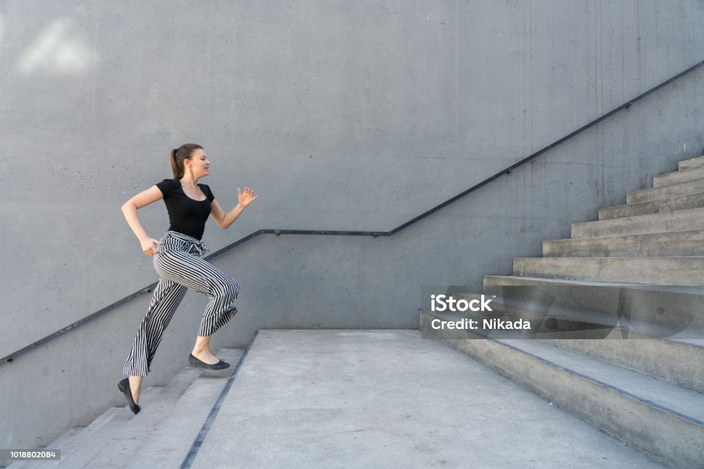 Woman running up steps in urban setting Staircase Stock Photo