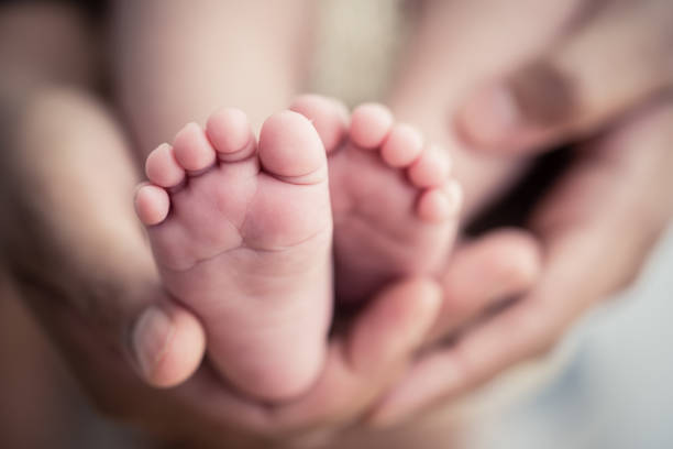 piedi di un neonato nelle mani dei genitori. buona famiglia oncept. mamma e papà abbracciano le gambe del loro bambino. - cute kid foto e immagini stock