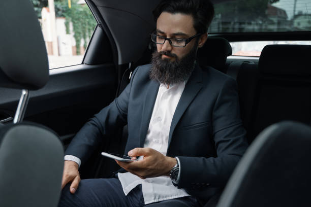 istock A businessman while traveling by car in the back seat using a sm 1018811544