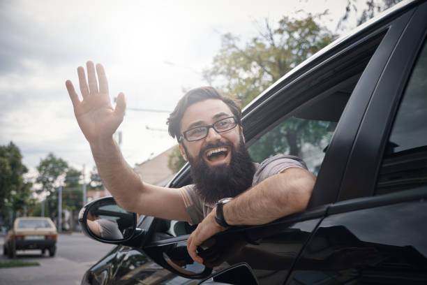 istock Cheerful man waving while driving a car 1018811750