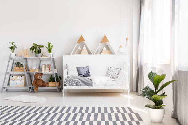 istock Patterned carpet and plant in white scandi bedroom interior with triangles above bed. Real photo 1018821012
