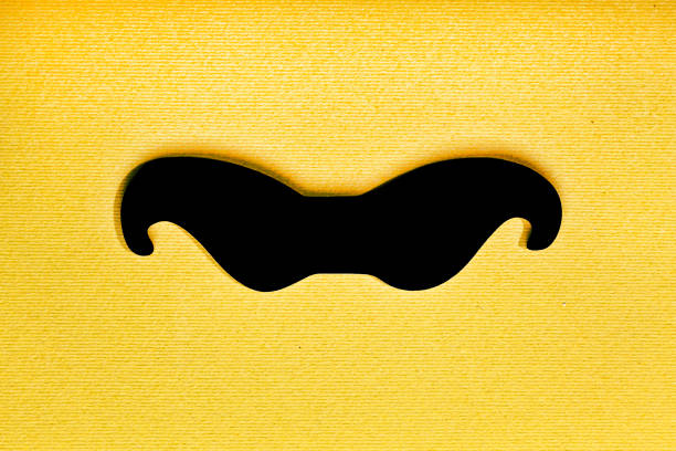 Father's Day, mustache. Minimalism. Black man's mustache on a yellow paper background. Symbol of Father's Day.