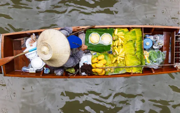 Photo of Damnoen Saduak Floating Market, Thailand small boats laden with colourful fruits and vegetables and paddled by Thai women wearing bamboo hats, The way of life of the villagers in the community.