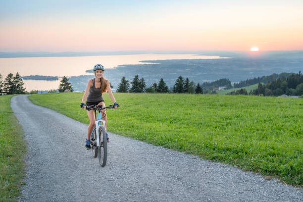 kobieta jazda na rowerze górskim w górę słynnej góry pfänder, jezioro bodensee (bodensee) z tyłu, austria - bregenzwald zdjęcia i obrazy z banku zdjęć