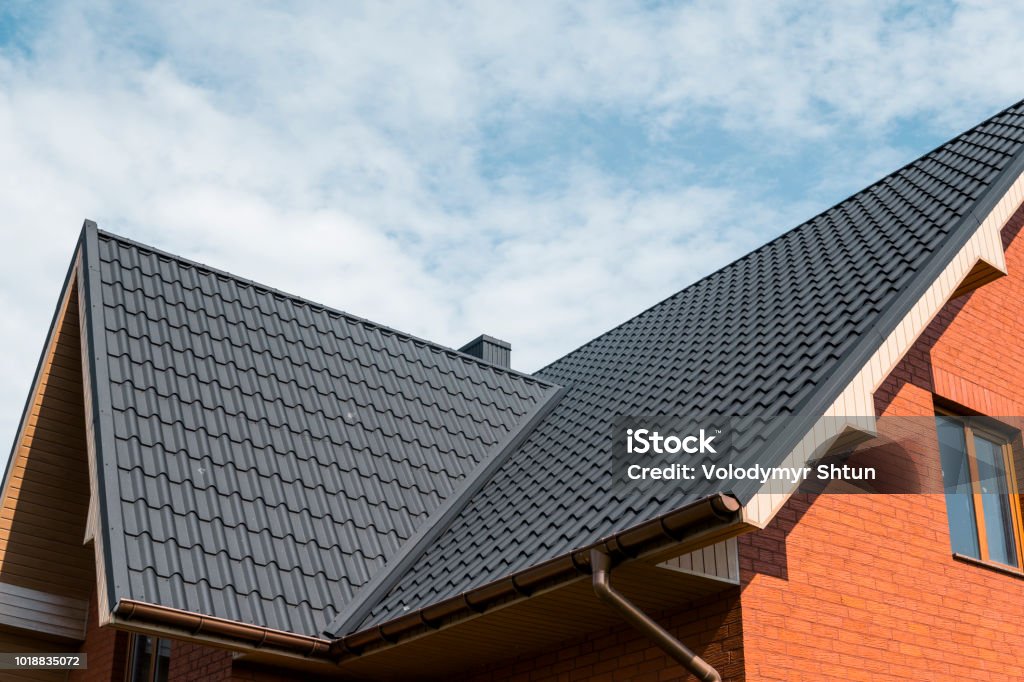 Modern roof covered with tile effect PVC coated brown metal roof sheets. Modern roof covered with tile effect PVC coated brown metal roof sheets Rooftop Stock Photo