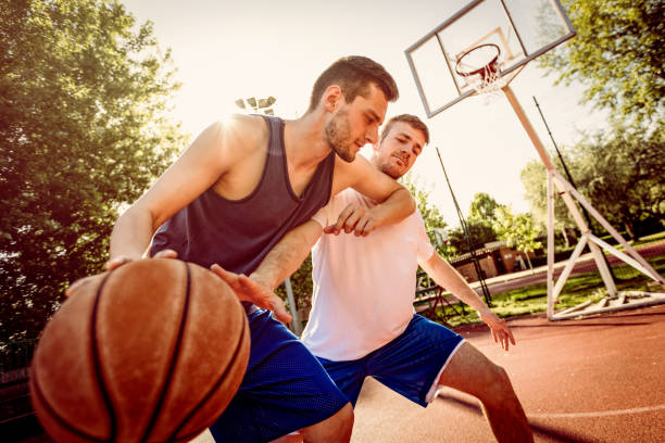 Basketball One On One Two street basketball players playing one on one. They are making a good action and guarding the ball. foul stock pictures, royalty-free photos & images