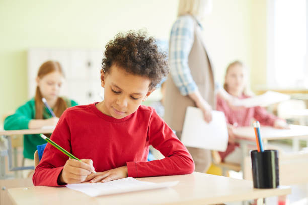 istock Confident schoolboy marking answers in blank 1018839248