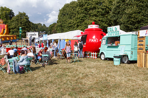 Bristol, UK: August 09, 2018: A Pimm's tea-pot shaped market stall advertising and selling the alcoholic drink Pimm's - attracts customers at a summer carnival during the holiday season at Bristol International Balloon Fiesta.