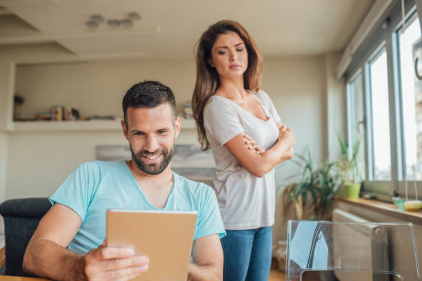 mujer joven busca celosamente en el hombre sonriente con tableta digital - standing digital tablet couple love fotografías e imágenes de stock