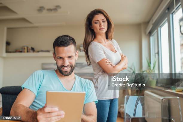 Young Woman Jealously Looking At The Smiling Man Using Digital Tablet Stock Photo - Download Image Now