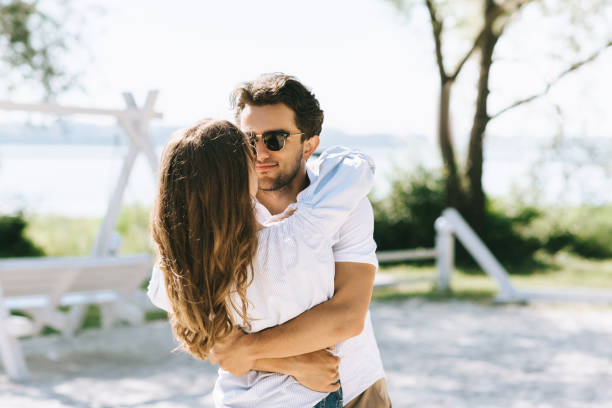 istock affectionate couple in sunglasses cuddling at city beach 1018851896