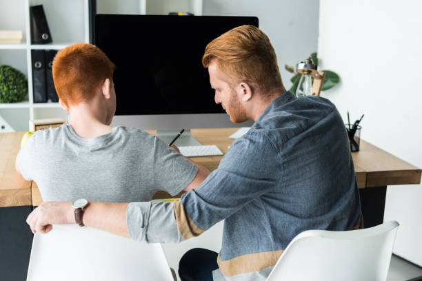 istock rear view of father helping son doing homework at home 1018863590