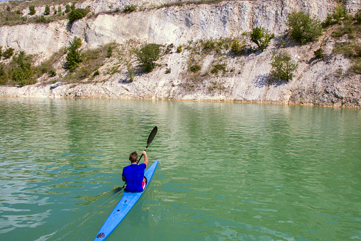 Kayaker paddling his kayak on a lake or river. Unrecognizable Caucasian male.