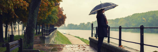 istock Woman with umbrella walking in the rain 1018869132