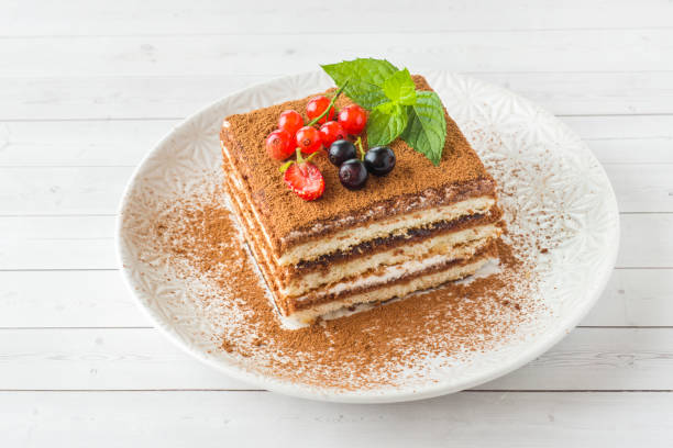 istock Delicious Tiramisu cake with fresh berries and mint on a plate on a light background. 1018881846