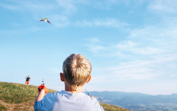 istock Boy and father start to fly a kite in sky over mountain hills 1018884158