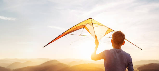 istock Boy prepare start to fly a kite over the sunset mountain hills 1018884216