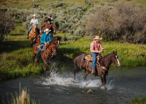 Cowboys riding across small river