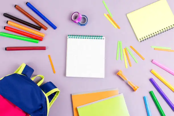 School concept flat lay. Kid backpack, notebook, markers on wooden desktop, top view