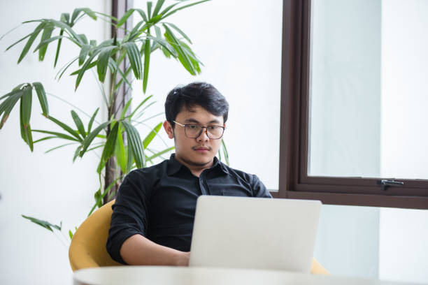 istock Young Asian businessman working on laptop in modern office. 1018925204