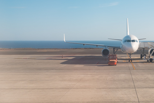front of airplane standing on runway with ocean background