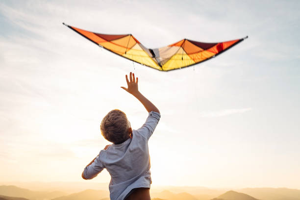 istock Boy start to fly bright orange kite in the sky 1018926140