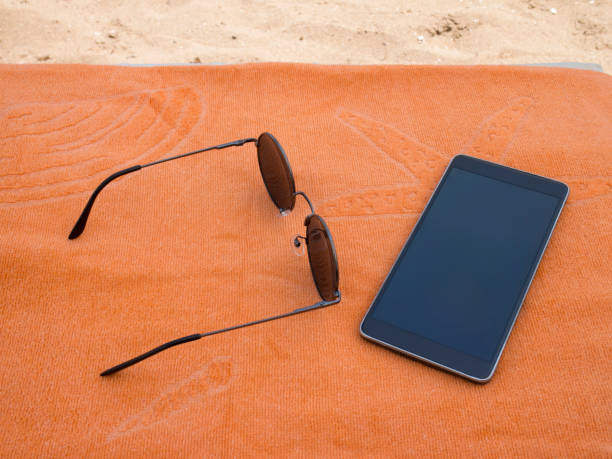 istock Sunglasses And Smartphone With Towel On Beach 1018926174