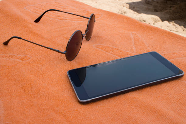 istock Sunglasses And Smartphone With Towel On Beach 1018926190