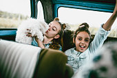 Girls Having Fun In Vintage Car And Kissing Little Dog