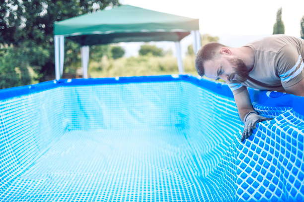 istock Male Worker Setting Up Pool Near Tent In Backyard 1018937120