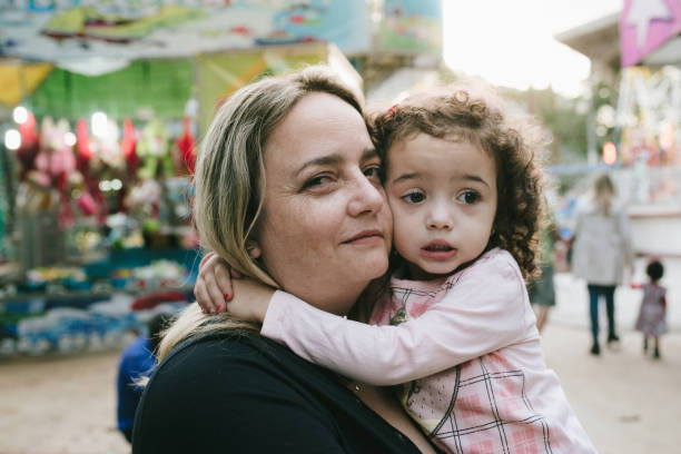 istock Mother and daughter hugging at amusement park 1018948246