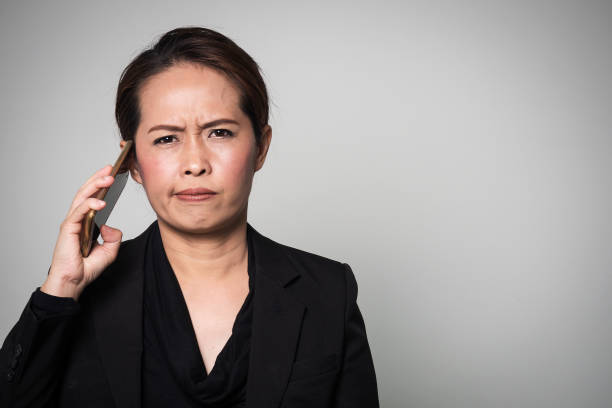 Middle adult Asian woman used smart phone. Action boring and take away from ear. Middle adult Asian woman used smart phone. Action boring and take away from ear. Portrait on white background with copy space. waiting telephone on the phone frustration stock pictures, royalty-free photos & images