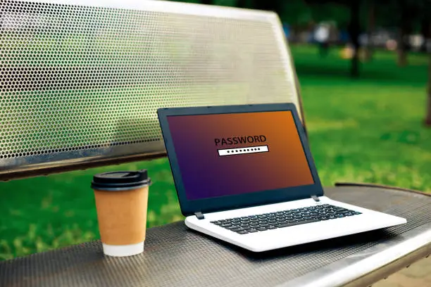 Photo of Password protected to login on the computer screen. Privacy Security Protection. Laptop on the bench in the park, blurred green trees behind